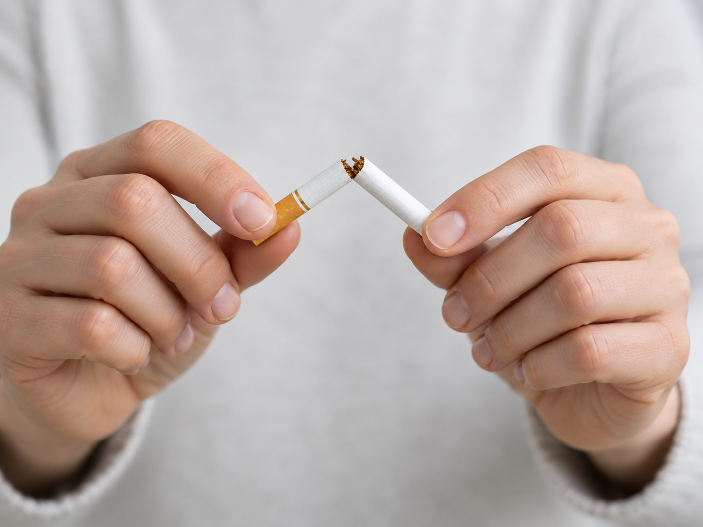 Persona rompiendo un cigarrillo como símbolo de dejar de fumar